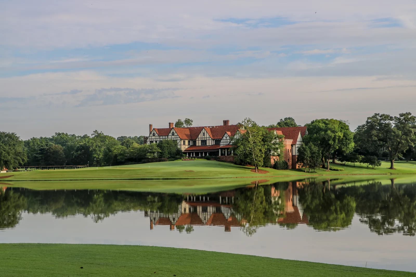 East Lake Golf Club's Tudor clubhouse reflected in the lake, seen from the eighth tee