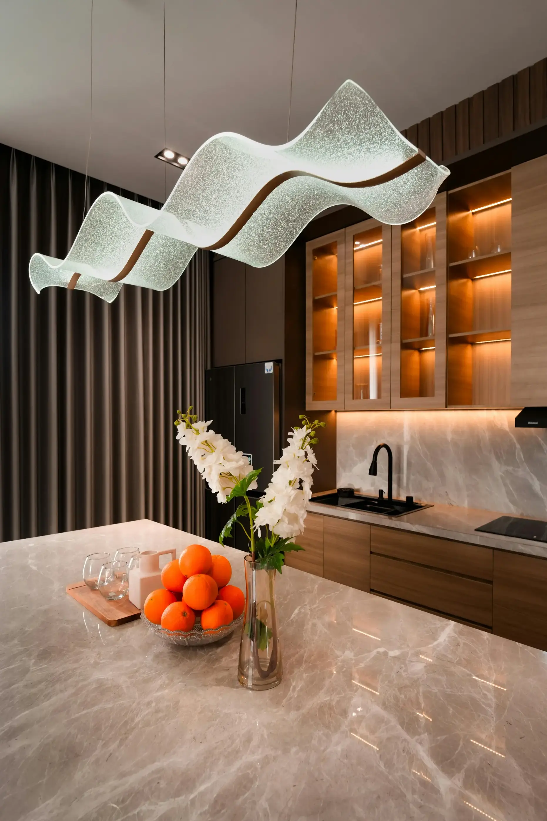 Modern Kitchen with Statement Pendant Modern luxury kitchen with sculptural glass pendant light and warm wood cabinetry