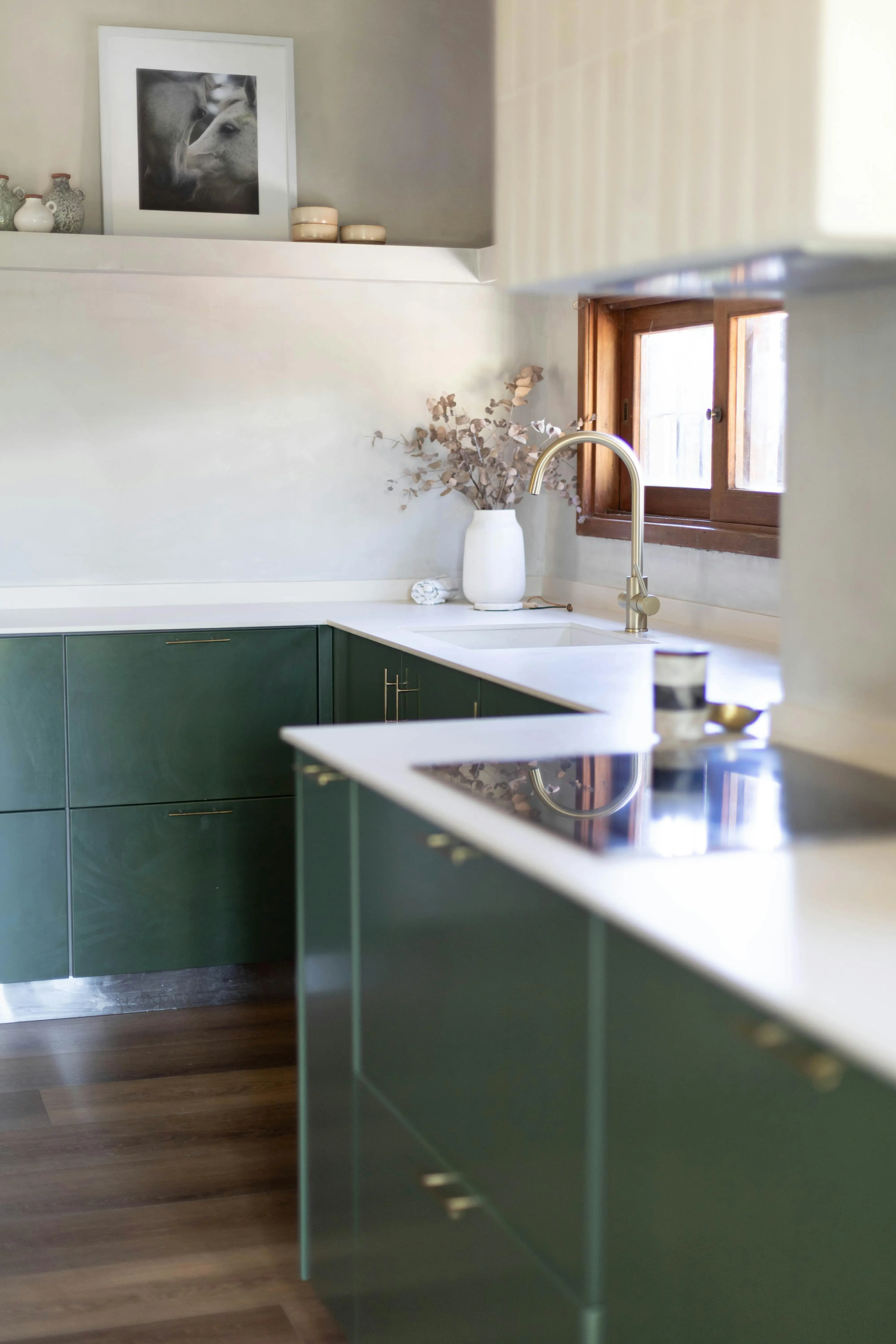 European-style kitchen with sage green cabinets, brass hardware, white quartz countertops and rustic wood window