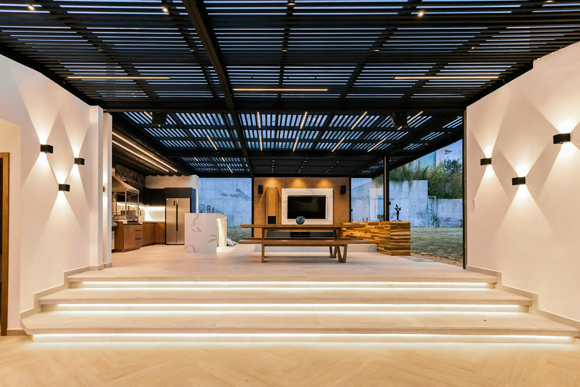 Covered outdoor living pavilion with LED-lit steps and modern pergola