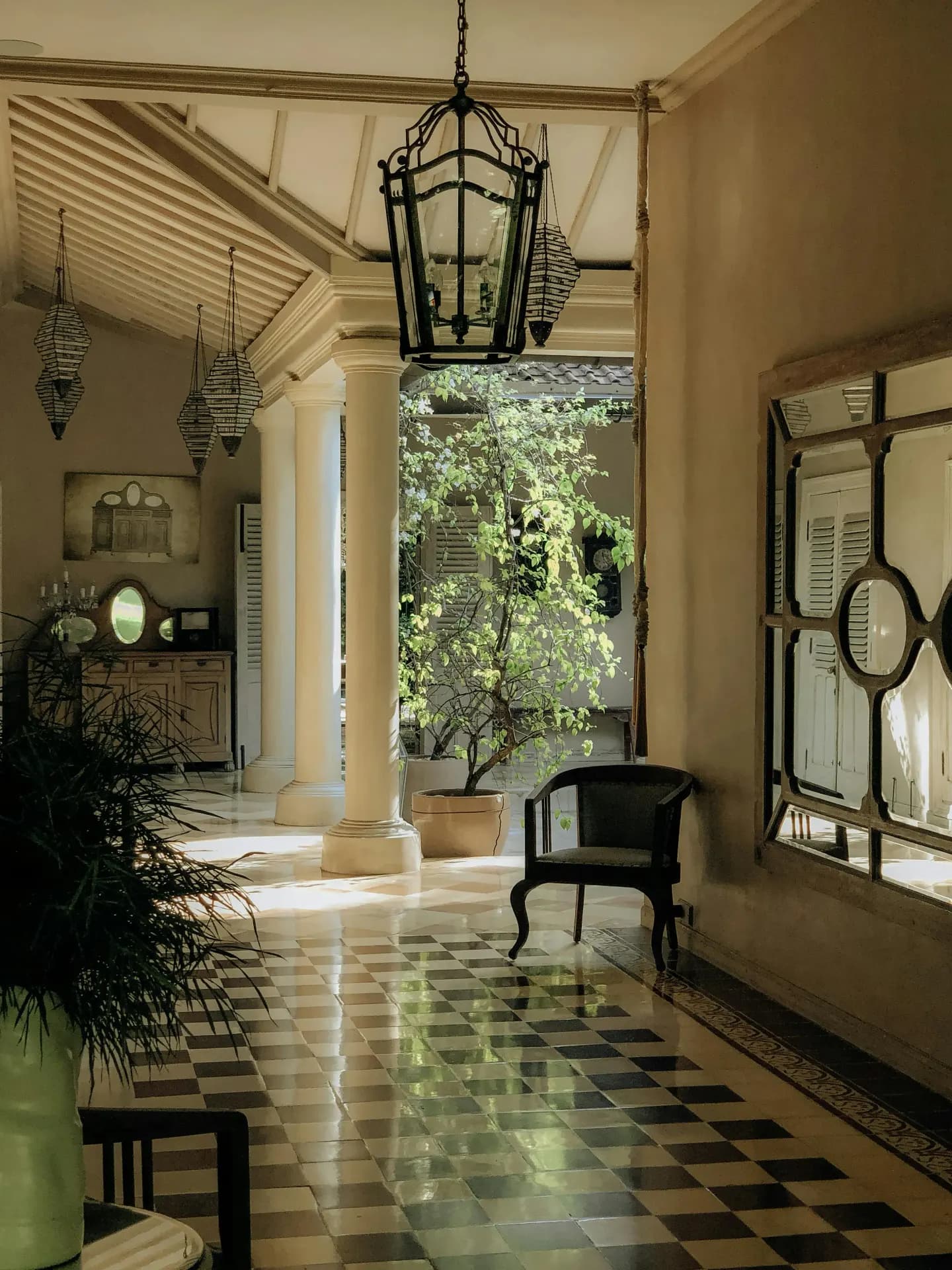 Colonial-style veranda with black and white checkered marble floors, lantern pendant and French shuttered windows